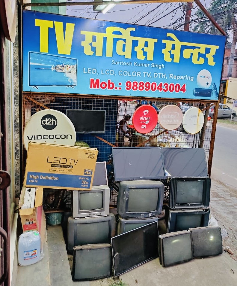 Televisions displayed beneath the blue TV Service Center signboard